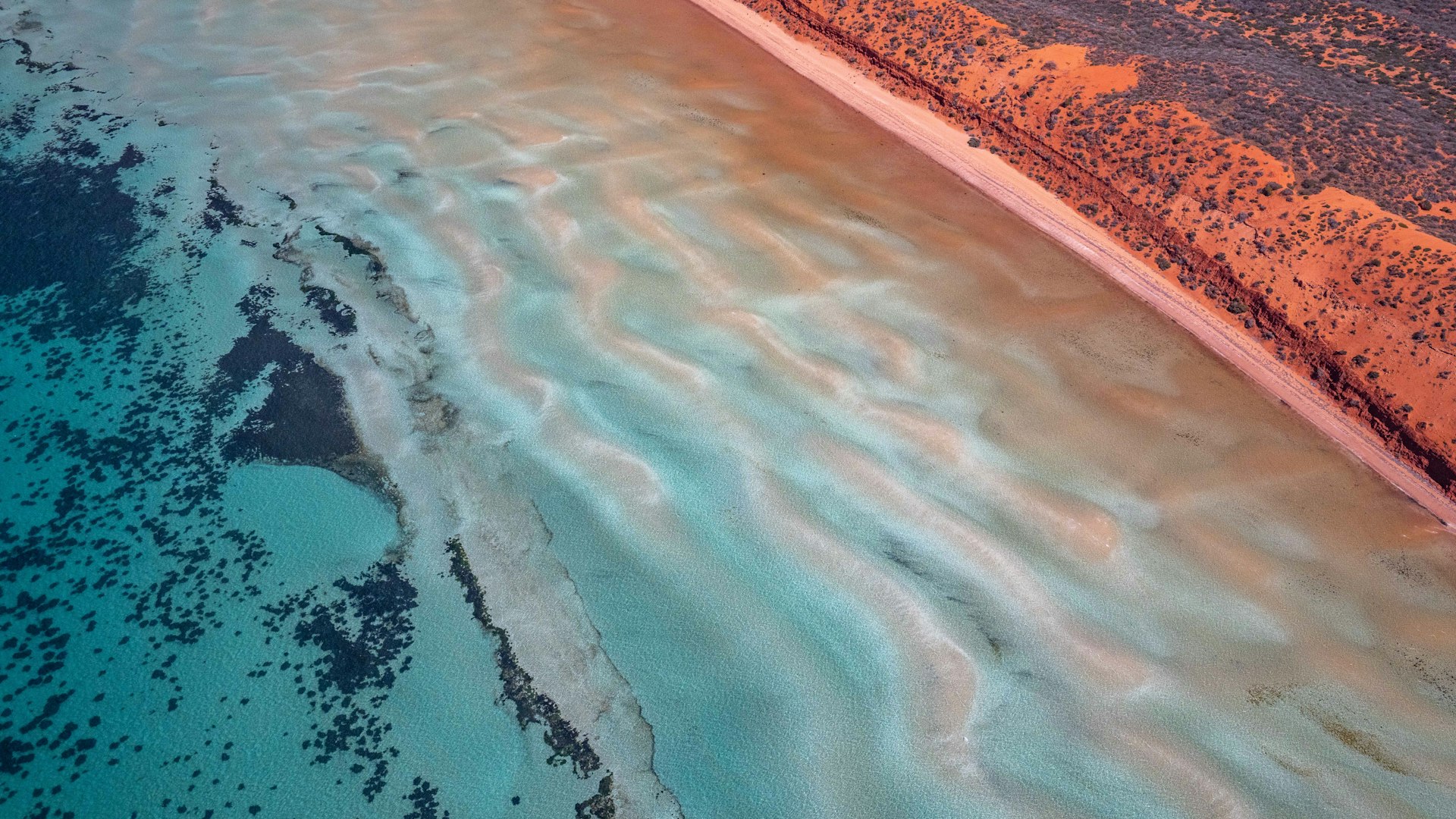 Aerial view of turquoise ocean water meeting a strip of sand