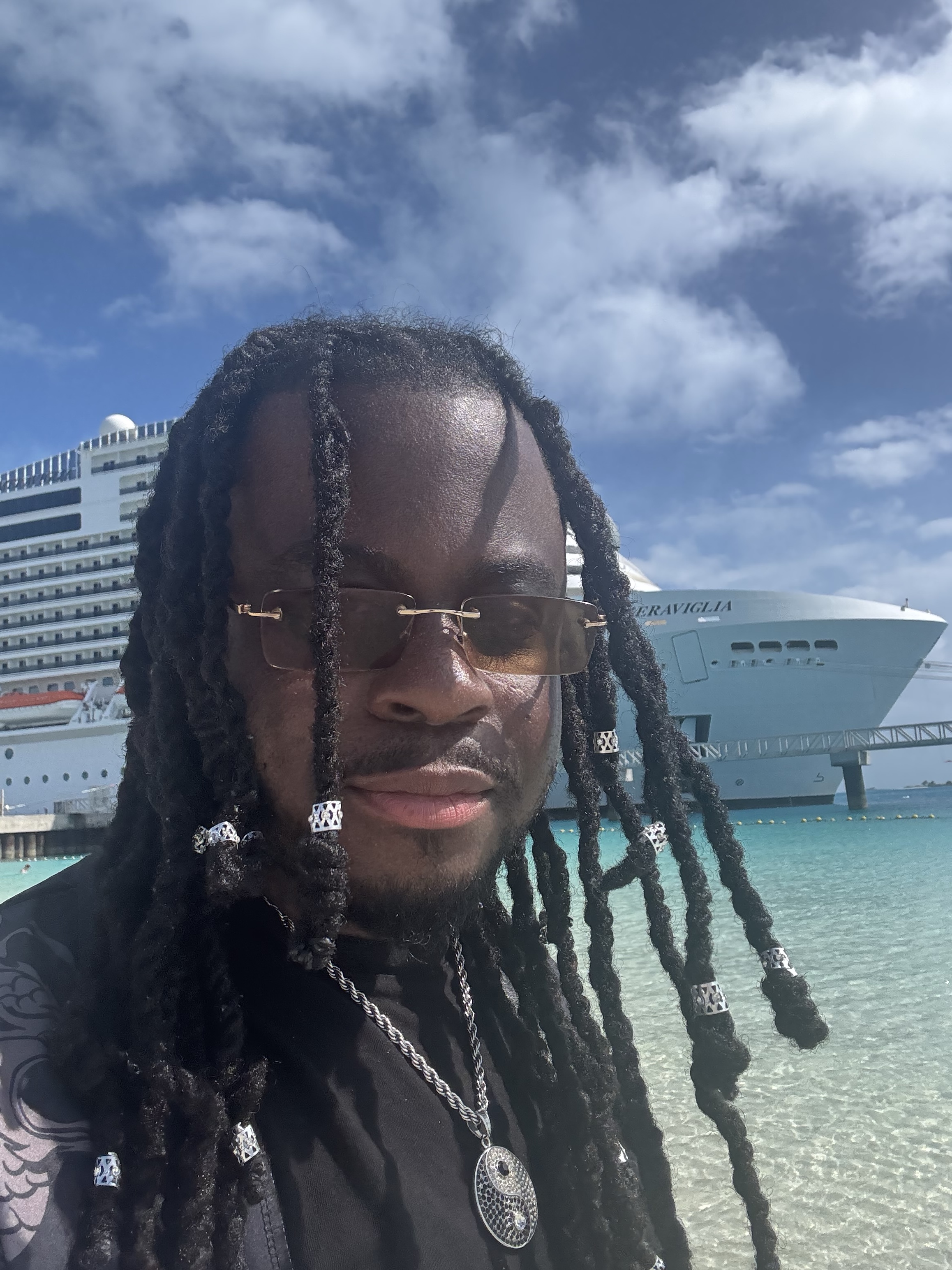 Marshall Delpé on a Bahamas beach with turquoise water and cruise ships behind him
